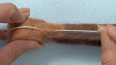 用手指握住金属丝，在金属丝周围戳上与底座颜色相同的毛毡